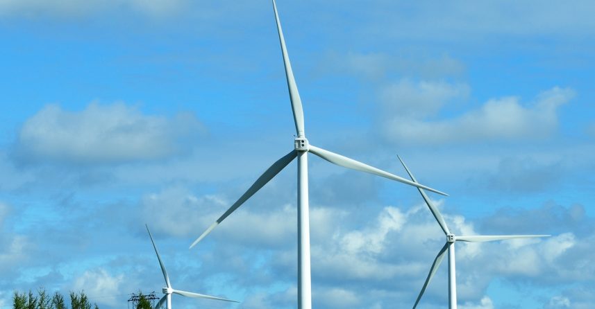 Wind turbines with a blue sky in the background and trees